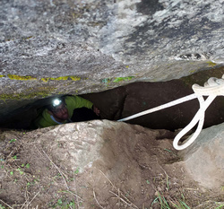 Uno speleologo nello strettissimo ingresso della grotta